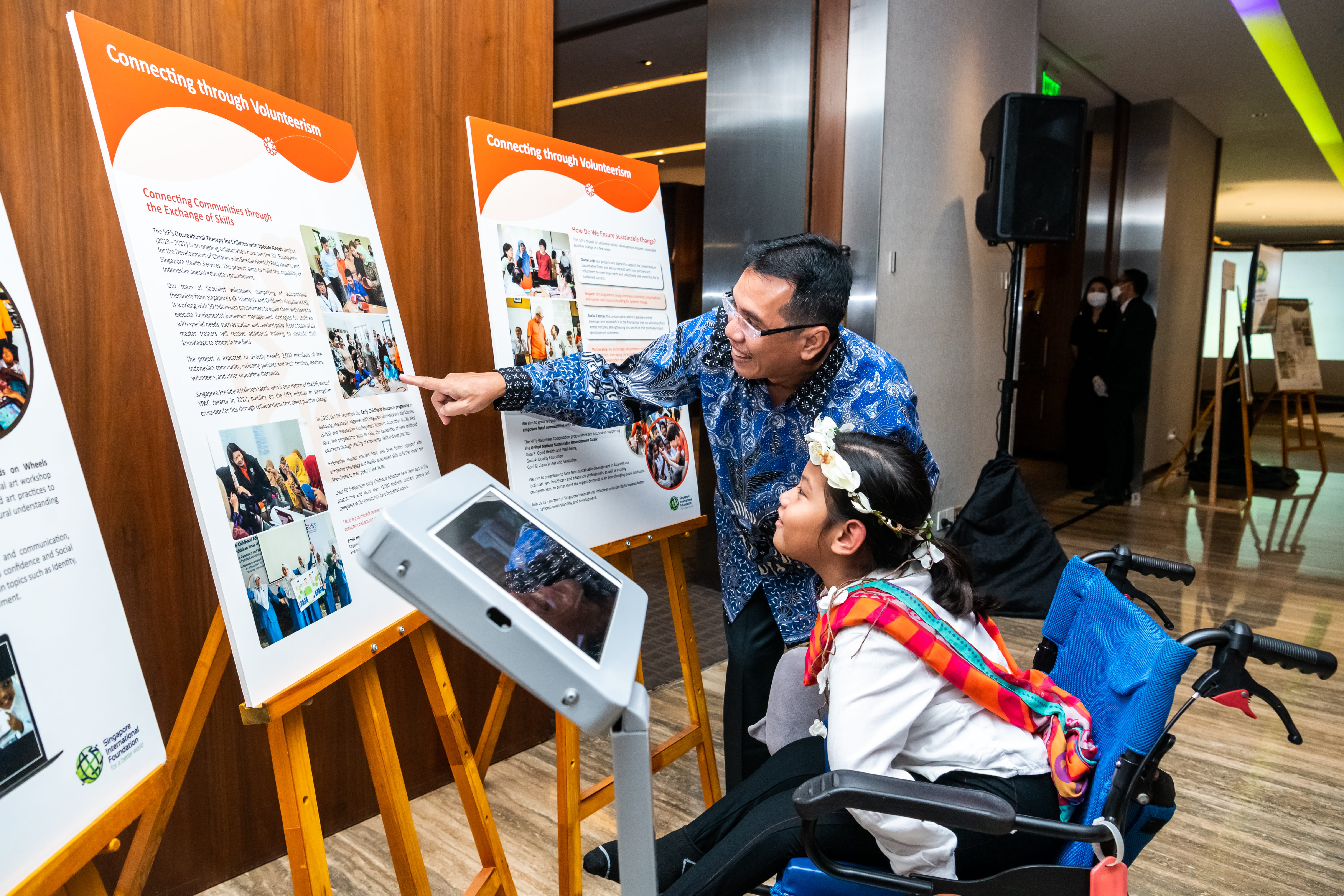 Mr Agoes Abdoel Rakhman, Managing Director, YPAC Jakarta showing his student a photo of the ‘Occupational Therapy for Children with Special Needs’ project, a collaboration between the SIF and YPAC Jakarta aimed to enhance support for children with special needs in Jakarta.