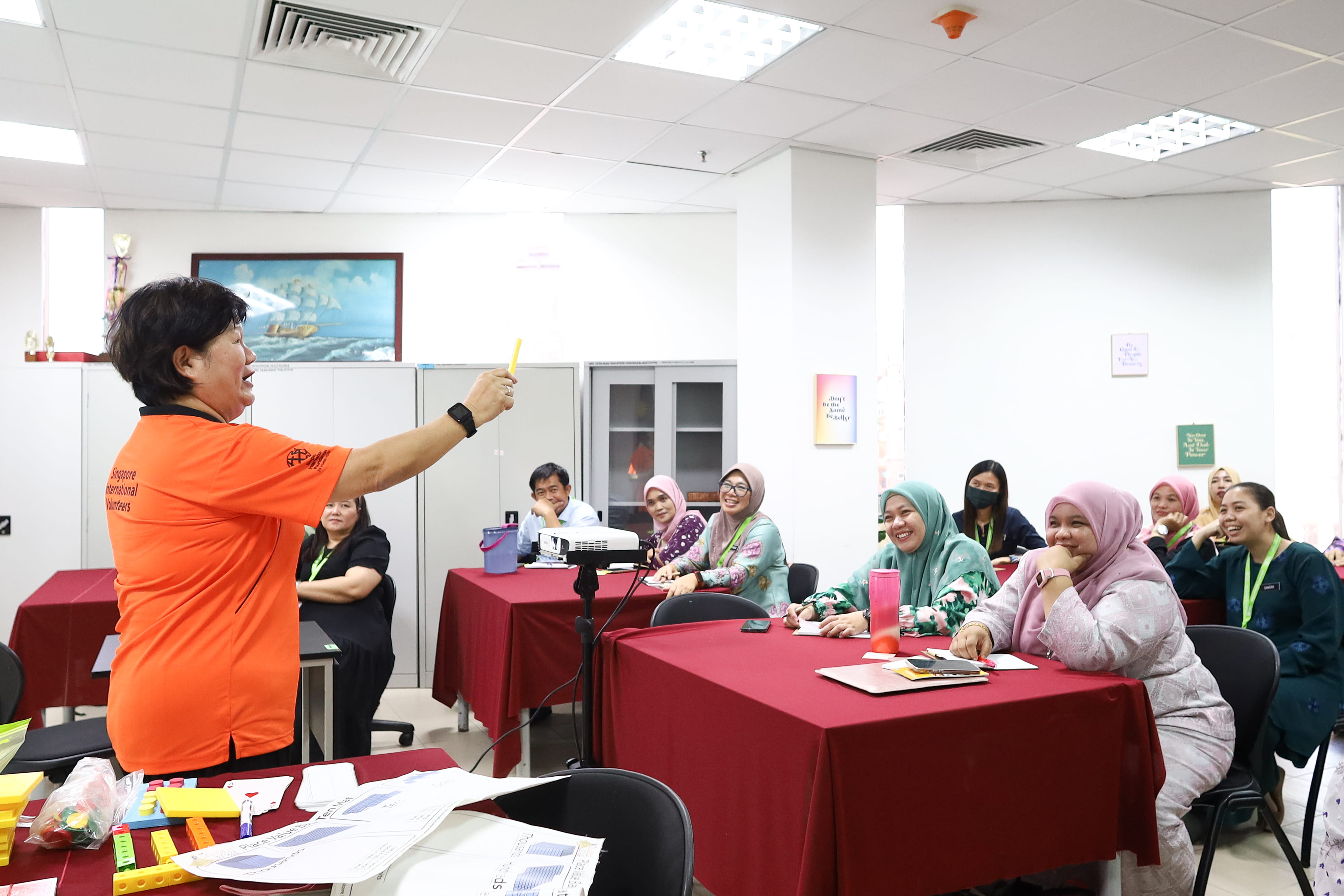 SIV Ms Juliana Donna Loh (in orange) demonstrating the use of Base Ten Blocks, an educational tool that helps students to visualize numbers, at the first Maths PLUS workshop.