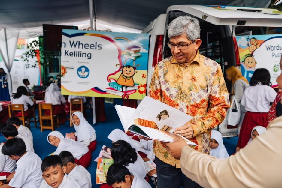 Dr Yaacob Ibrahim (centre) reading one of the 2,000 books available in the mobile library under the WoW (Yogyakarta) programme
